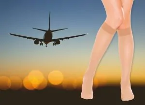 A plane coming in to land at sunset, beside a pair of legs wearing sheer nude compression knee highs